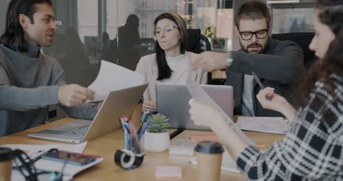 Group of Businesspeople Colleagues Talking and Distributing Documents Sitting at Desk in Office