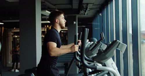 Young Man Exercising on Elliptical at Modern Gym
