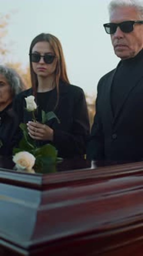Mourners Placing Roses on Coffin Outdoors