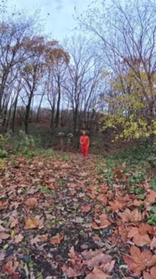Woman Dancing in Autumn Woods Wearing Orange Jumpsuit