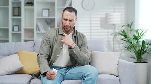 Sweaty man in hot weather is sitting at home on the sofa, he is hot and he turns on the air