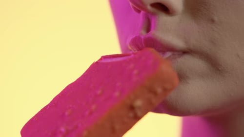 Close Up Of Woman's Mouth Eating Flavor Popsicle Ice Cream Against Yellow Background