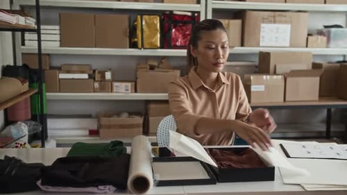 Online Store Worker Packing Clothes in Box before Shipping