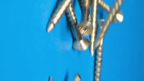 Screws Falling on Blue Surface Close Up