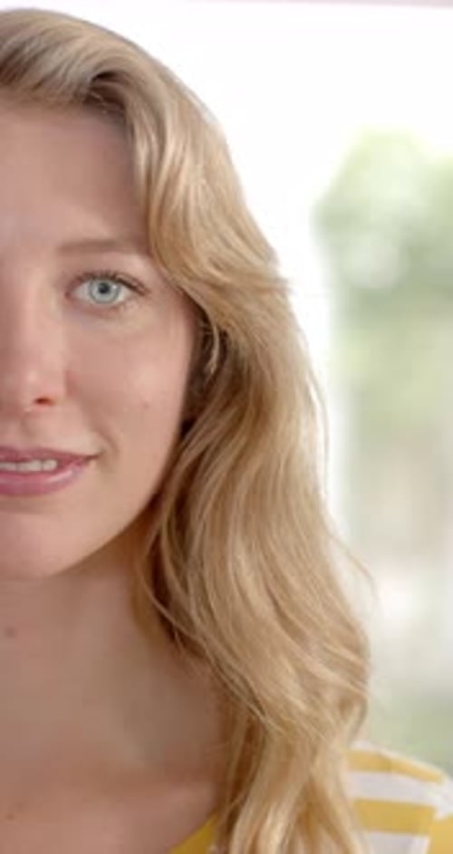 Vertical video of portrait of caucasian woman with blond hair at home, slow motion