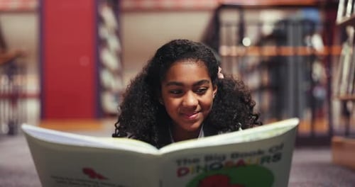 Education, happy and child with reading book in library, learn vocabulary and language development