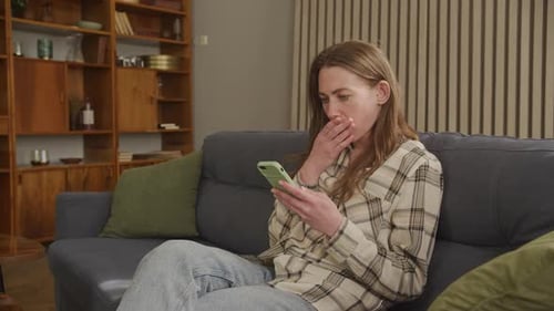 Young Woman Relaxing on Couch Using Smartphone