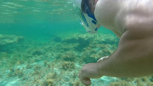 Handheld Underwater View of a Young Man Snorkeling in a Shallow Area of The Mediterranean Sea