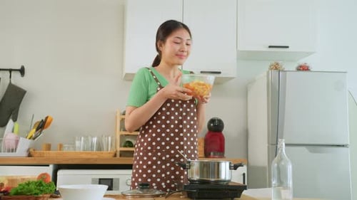 Young Woman Cooking Food in Bright Kitchen