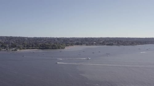 Aerial fly over from English Bay to Kitsilano Beach on a hot summer day as boaters relax suntan lies