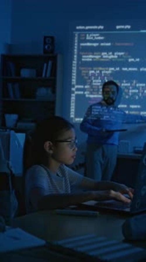 Schoolgirl Writing Computer Code during Lesson and Listening to Teacher