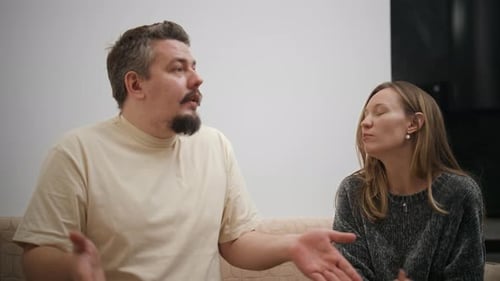 Man and Woman Discuss Something on Couch Indoors