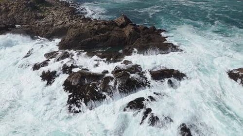 Aerial View Of Powerful waves are crashing against a rocky shore, creating a dramatic scene of natur