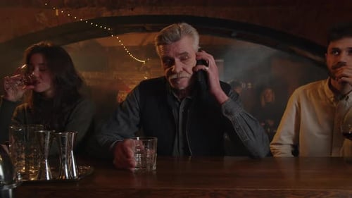 Three People Drinks at the Bar Counter Adult Man Answer Cellphone While Sitting Inside Cafeteria