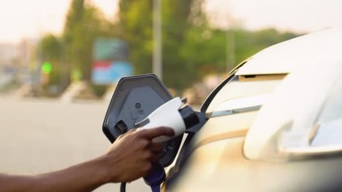 Schwarzer Mann trennt den Stromanschluss vom Lasten-Elektroauto aus nächster Nähe