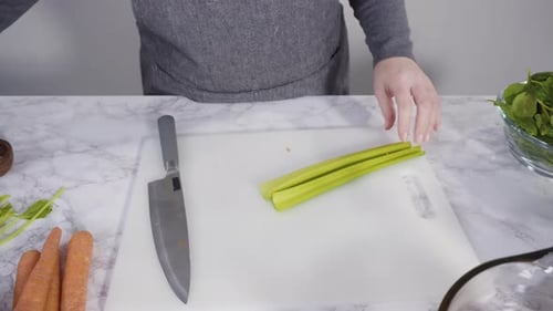 Woman cuts celery on a countertop