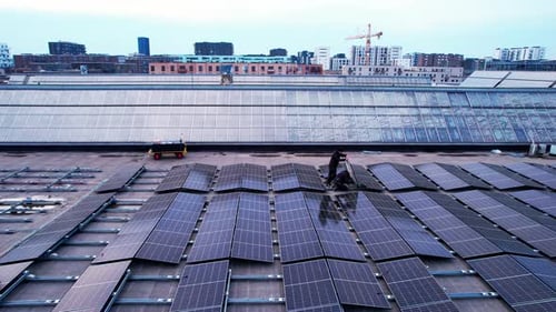Aerial footage of two solar cell technicians maintains, install and repair solar cells on a rooftop