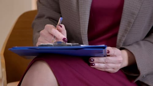 Gros plan d'une psychothérapeute prenant des notes dans le bloc-notes pendant la session