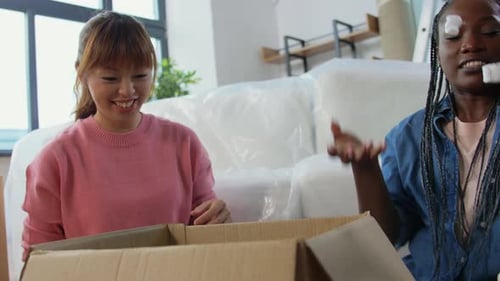 Moving, People and Real Estate Concept - Women Unpacking Boxes, Throwing Foam