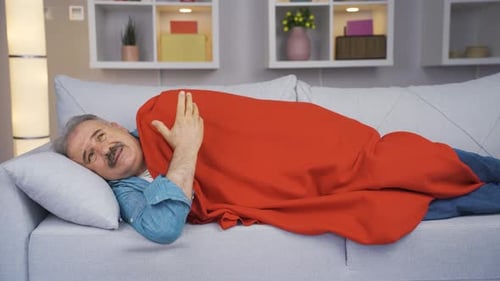 Man Lies on Couch Under Red Blanket
