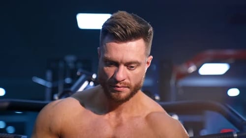 Handsome man with big muscles, posing on the camera in the gym. Slow motion.