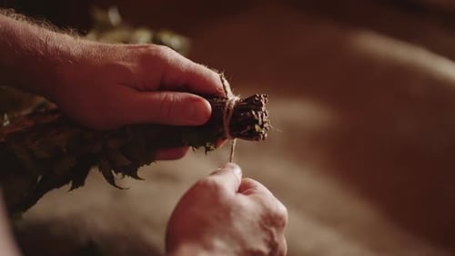 Traitements de spa dans un bain de vapeur traditionnel Vue rapprochée des mains d'un maître fabriquant un balai en bouleau
