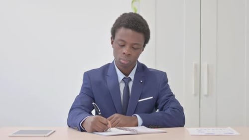 Young African Businessman Writing Letter in Office
