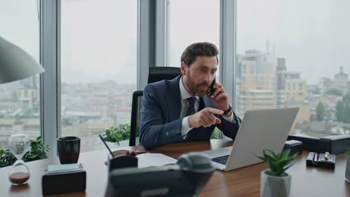 Businessman Talking on Phone and Using Laptop