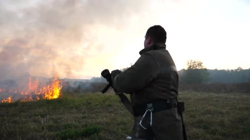 Firefighter Extinguishing Brush Fire at Sunset