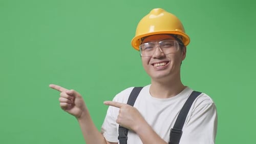 Man Worker Wearing Goggles And Safety Helmet Smiling And Pointing To Side In The Green Screen