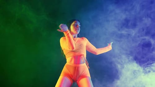 Verführerische Frau tanzt sexy Bewegungen in neonengem Kostüm Verführerischer Tanz im mehrfarbigen Lichtstudio
