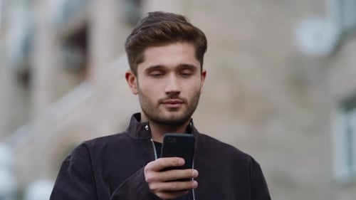 Closeup Surprised Guy Using Mobile Phone on City Street. Portrait of Smiling