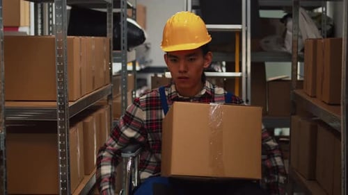 Asian Wheelchair User Working in Warehouse Space