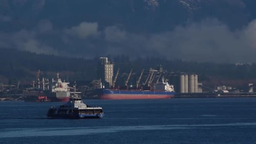 Passenger ferry crossing the Vancouver harbour with in the background two giant multi purpose vessel