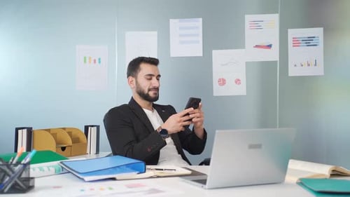 Man Using Smartphone at Desk in Modern Office