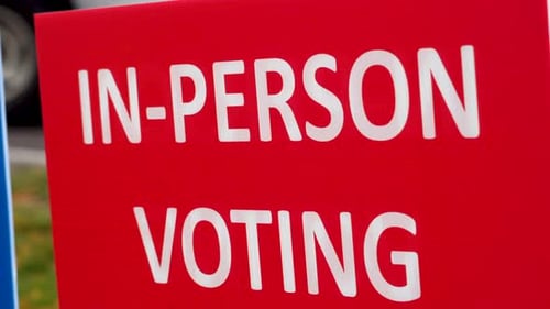 Red In-Person Voting Sign Blowing in the Wind Outside Close Up