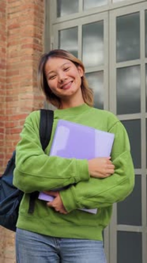 Cheerful Young Student Happily Holding Purple Folder While Smiling and Preparing for University