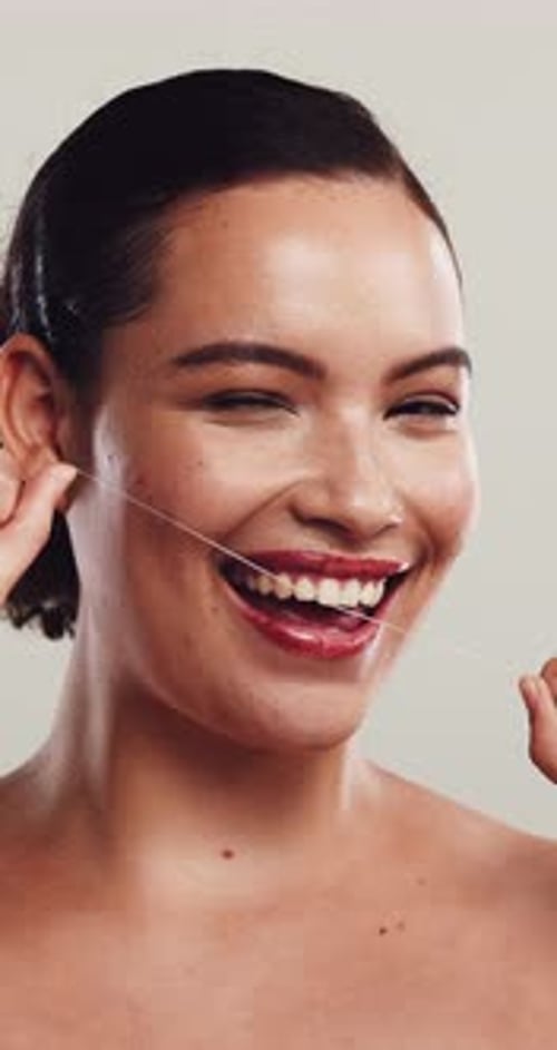 Face, wink and woman in studio, floss and dental hygiene with wellness on white background