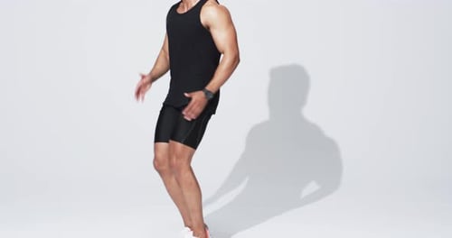 Athletic young biracial man running in place on white background, with copy space