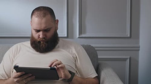 Man Using Tablet at Home on Couch