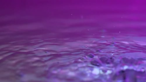 Wunderschöne, klare, bunte, neonbeleuchtete Regentropfen auf der Wasseroberfläche, die von oben fallen und Regenschauer erzeugen