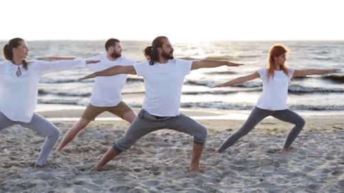 Yoga class reaches serenity in warrior pose on a beautiful beach at sunset