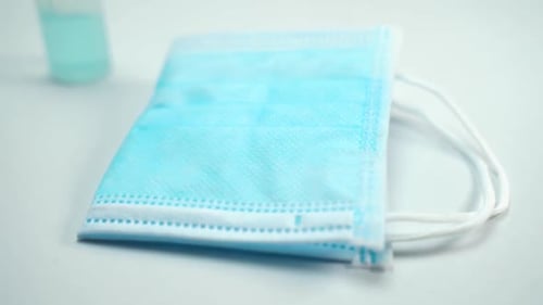 Close up of single blue face mask and small bottle of sanitize hand gel is prepare to use to prevent