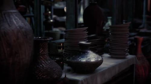 Antique Pottery and Plates Displayed in a Dimly Lit Market Setting