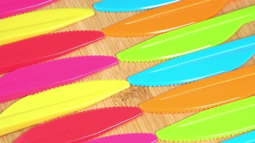Colorful Plastic Picnic Knives on Bamboo Background