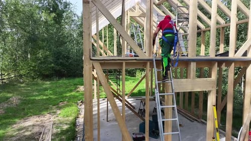 Construction Worker Using a Miter Saw on a Ladder