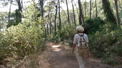 Woman Hiking Through Forest Path with Backpack