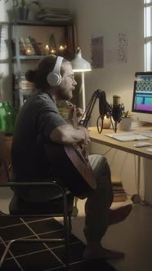 Musician Recording Song with Guitar in Home Studio