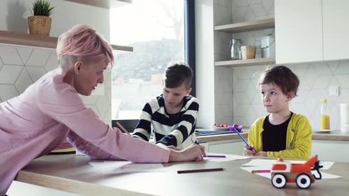 Woman with children drawing at kitchen table together