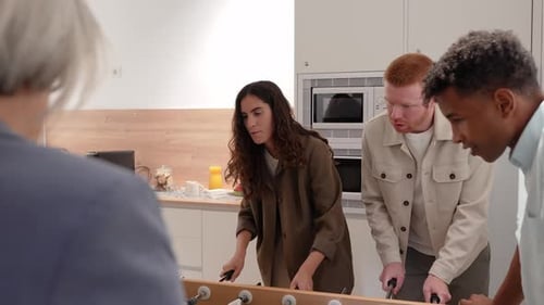 Enthusiastic Colleagues Play Table Football Game in Office